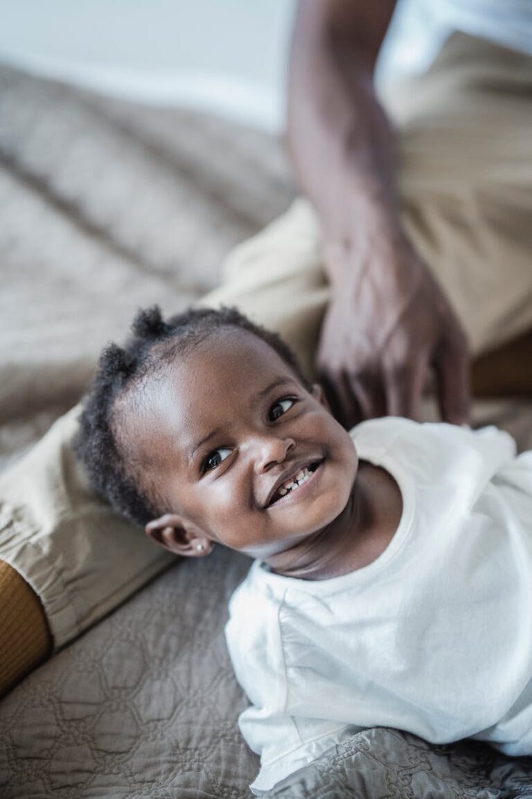 portrait of a smiling baby girl lying down on bed