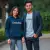 Couple, lui portant le sweat à capuche imprimé "EmakoBollo" en Navy Blazer, elle portant un t-shirt EmakoBollo, se tenant la main et souriant.