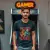 Photo : Luc V (homme) arborant le t-shirt gamer geek, posant devant une borne d'arcade rétro.