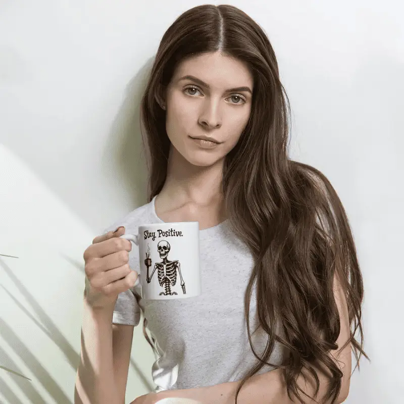 Mug pas cher blanc skeleton halloween imprimé stay positive tenu par une femme avec des longs cheveux.