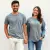 Photo d'un couple souriant, main dans la main arborant chacun un t-shirt classique gris pincard