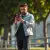 Photo dynamique d'un homme utilisant son iPhone avec la coque 'I Love You' en mouvement, montrant la facilité de prise en main et la discrétion de la coque. Lumière du jour.
