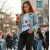 Photo dynamique d'une femme utilisant son iPhone avec la coque imprimée 'I Love You' en mouvement, montrant la facilité de prise en main et la discrétion de la coque. Lumière du jour.