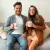 Photo : Un couple souriant, chacun tenant un mug "I Love You" latte, assis sur un canapé confortable