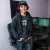 Photo : jeune homme portant la casquette, souriant devant son setup gaming