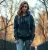 une jeune femme portant le pull à capuche "Game Over" de couleur carbon grey, en pleine nature ou dans un environnement urbain décontracté