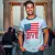 photo d'un homme souriant, portant le T-shirt Love, peut-être devant un monument emblématique