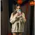 une jeune femme souriante, posant avec son iPhone et sa coque, un décor d'Halloween en arrière-plan discret)