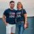 une photo d'un couple souriant, portant chacun un T-shirt americain, peut-être lors d'un voyage